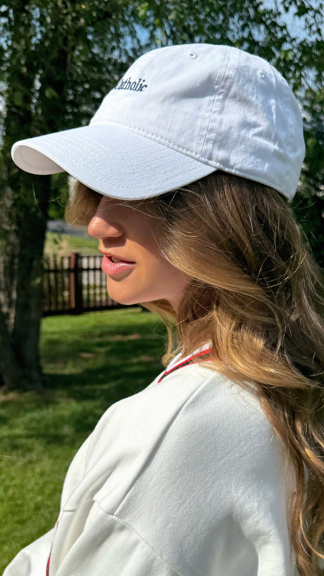 Person wearing a white cap outdoors with trees in the background